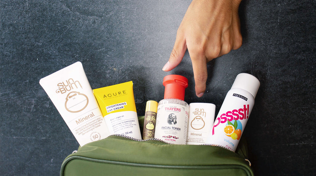 hand grabbing travel skincare products from dopp kit