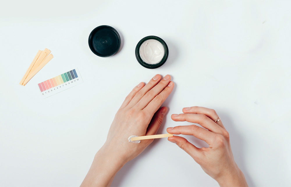 Hands testing moisturizer ph with litmus paper