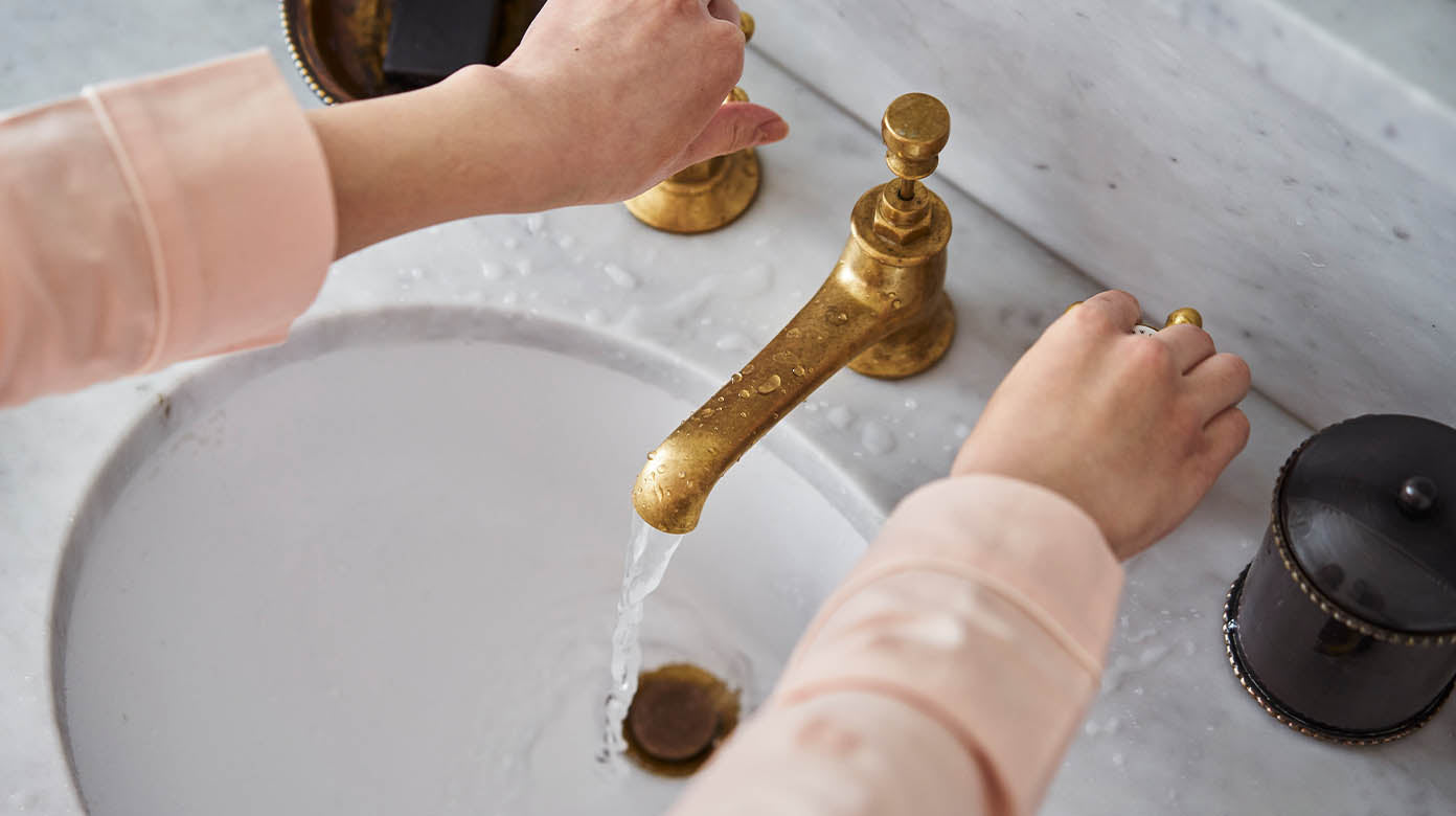 Hands turning on sink